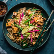 overhead view of vegan pad thai with tofu in a blue bowl with chopsticks.