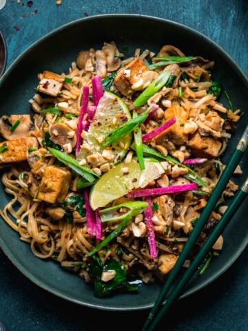 overhead view of vegan pad thai with tofu in a blue bowl with chopsticks.