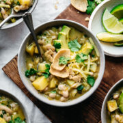 overhead view of bowl of vegan white bean chili topped with avocado and corn chips.