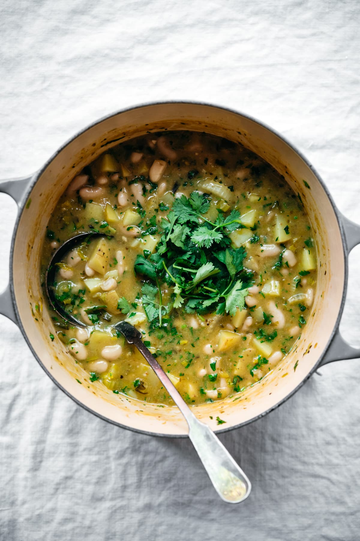 overhead view of vegan white bean chili in a large pot topped with fresh cilantro. 