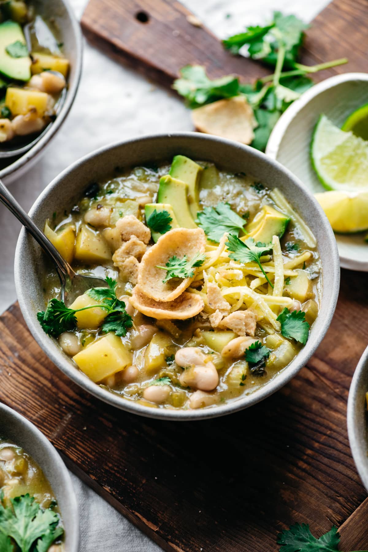 close up view of vegan white bean chili in a bowl topped with corn chips. 