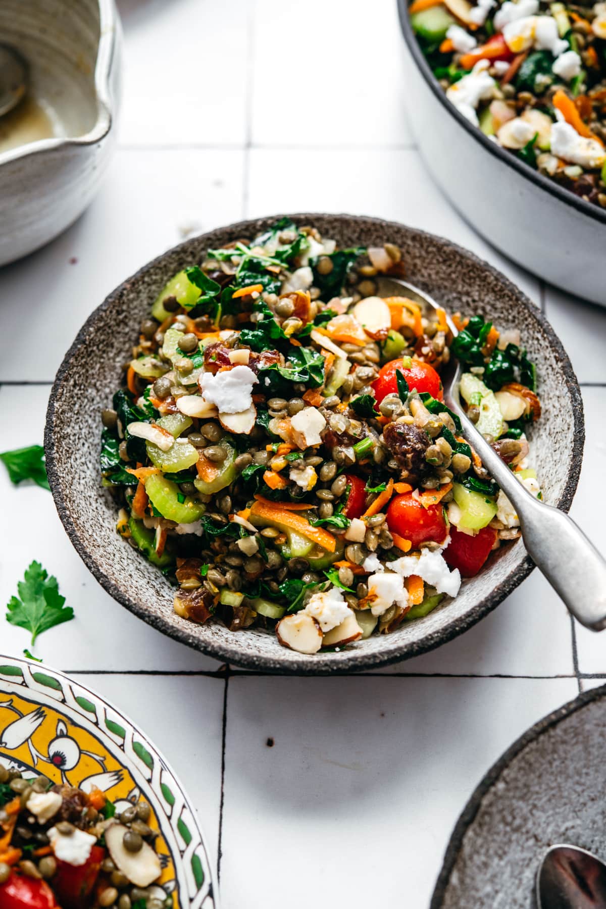 close up view of vegan french lentil salad in a small bowl with spoon on white tile background.