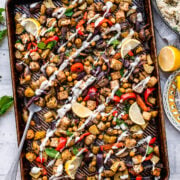 overhead view of vegan mediterranean sheet pan dinner with tofu, chickpeas, vegetables and tahini yogurt drizzle.