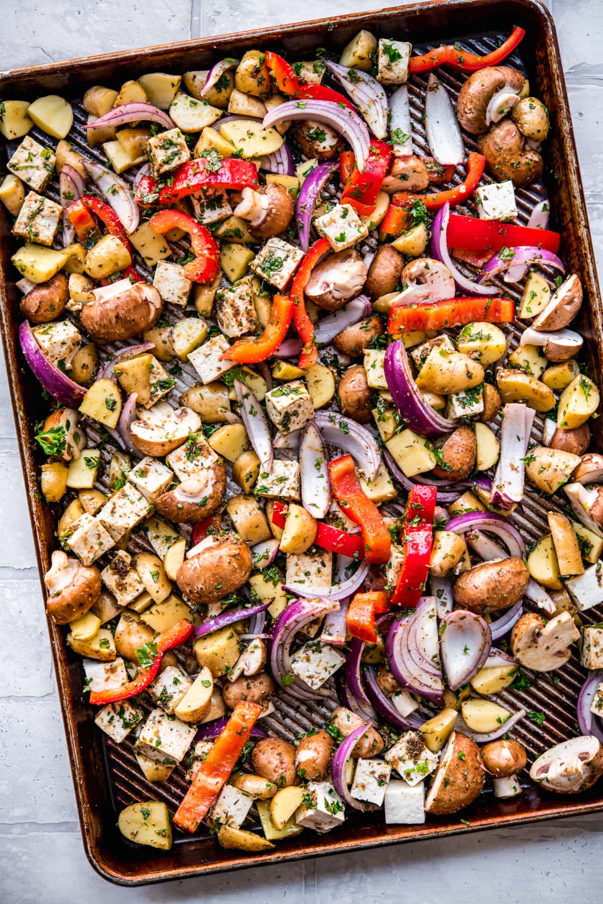 overhead view of vegan mediterranean sheet pan dinner with tofu and vegetables before roasting.