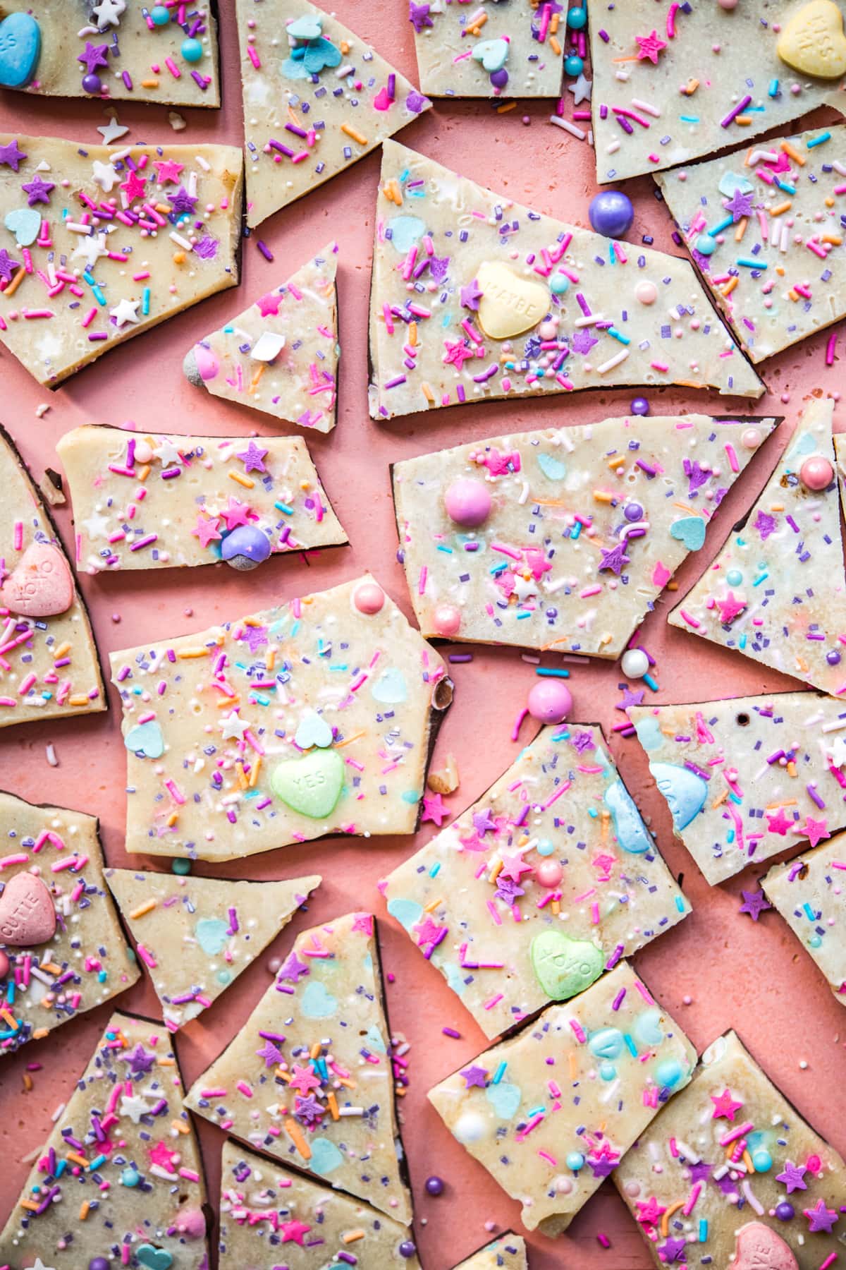 overhead view of vegan white chocolate bark broken into pieces topped with sprinkles.