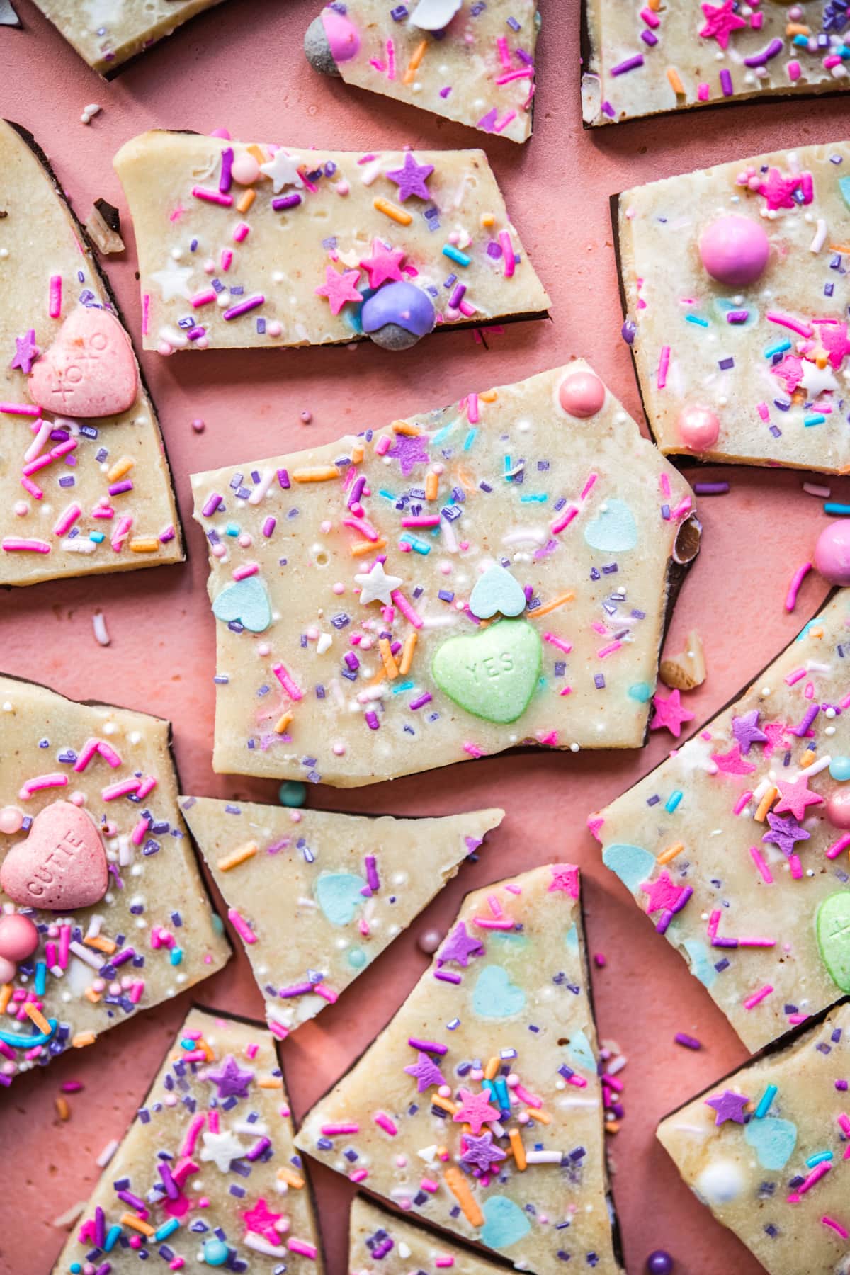 overhead view of vegan white chocolate bark broken into pieces topped with sprinkles.