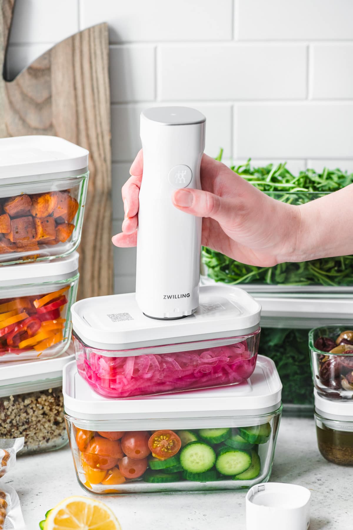 side view of person using Zwilling fresh and save vacuum sealer to seal salad meal prep materials. 