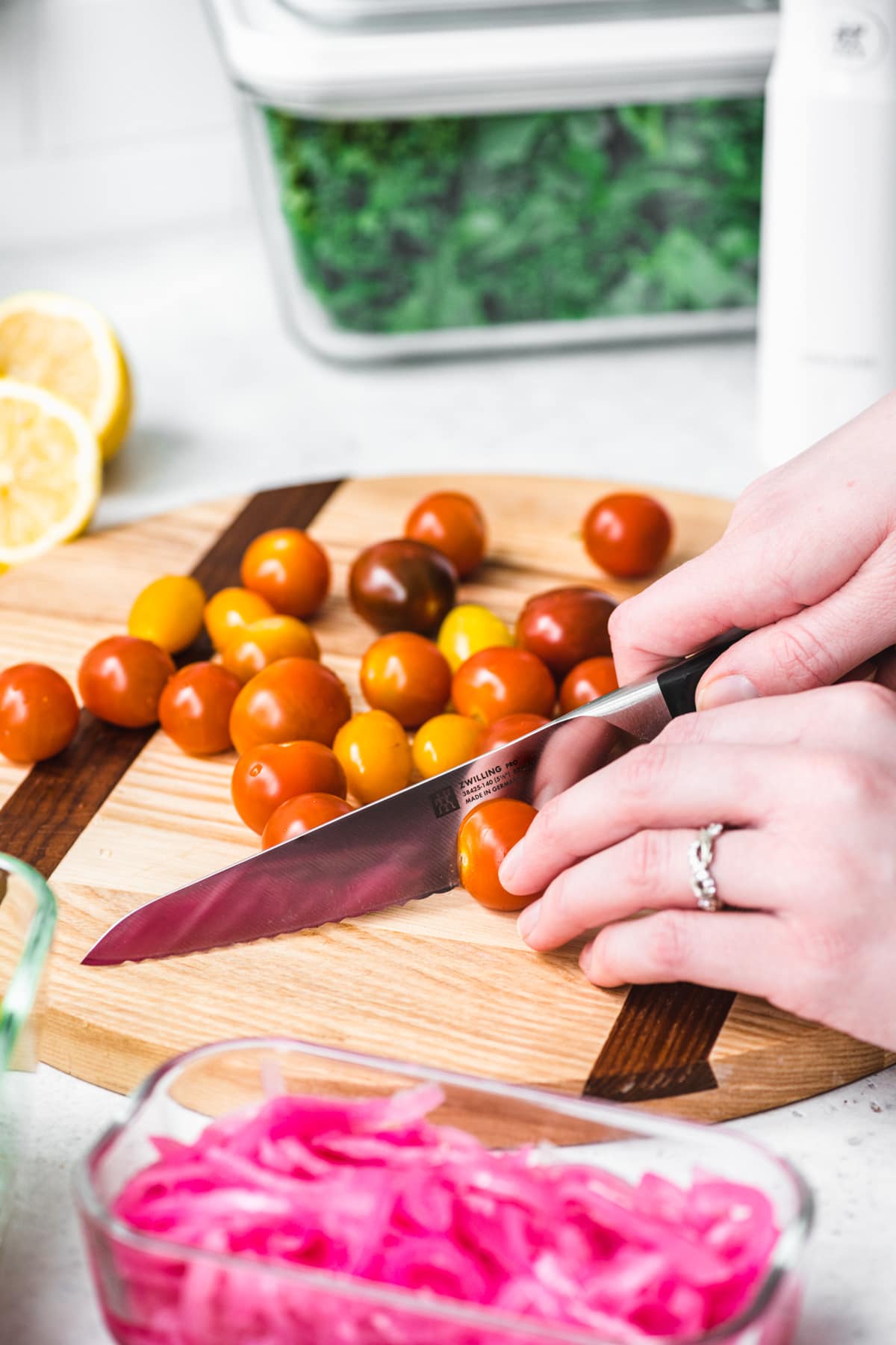 close up of person slicing cherry tomatoes in half. 