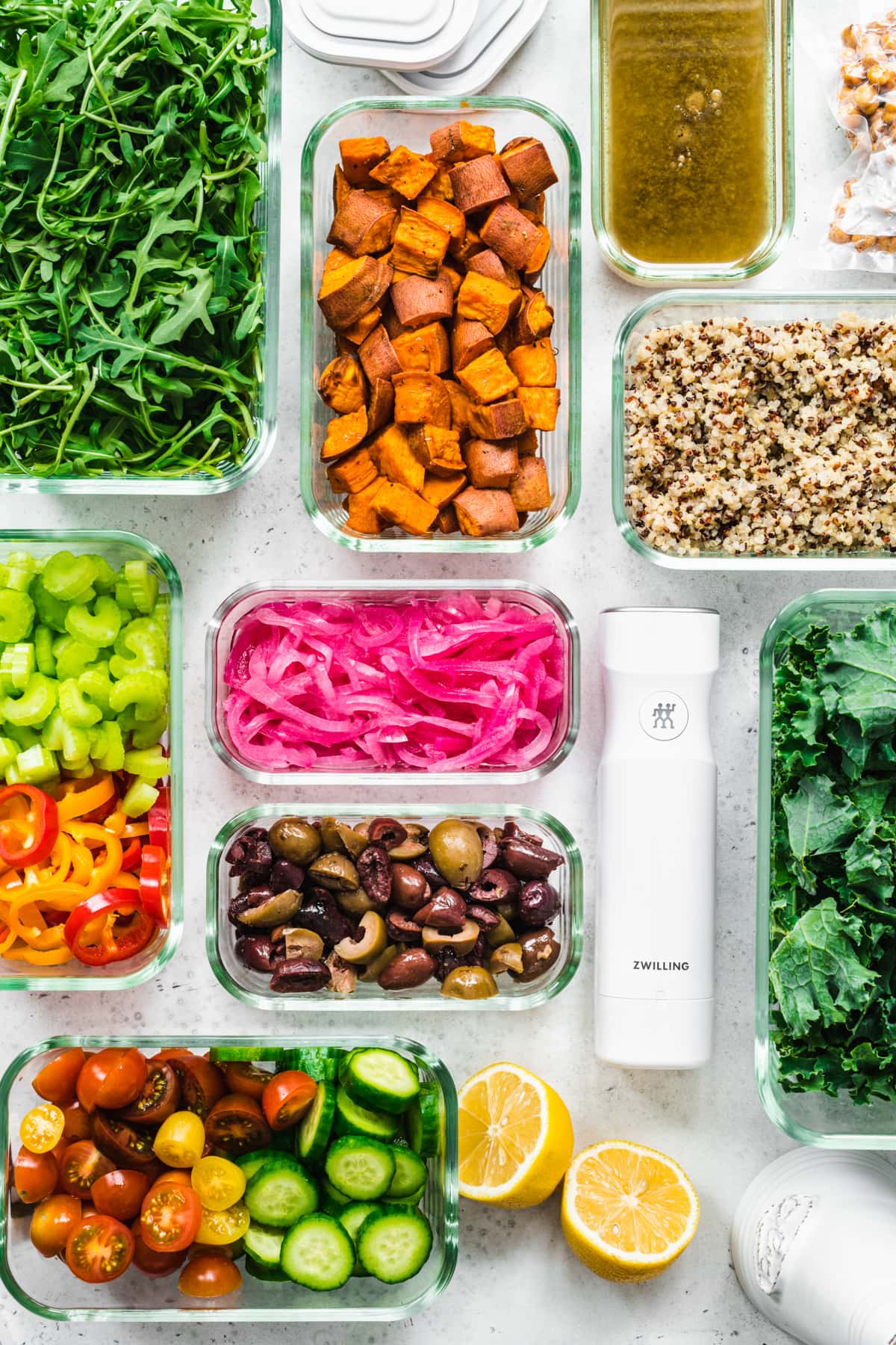overhead view of several meal prep containers filled with various salad ingredients, like roasted and raw sliced vegetables, greens, quinoa, etc.