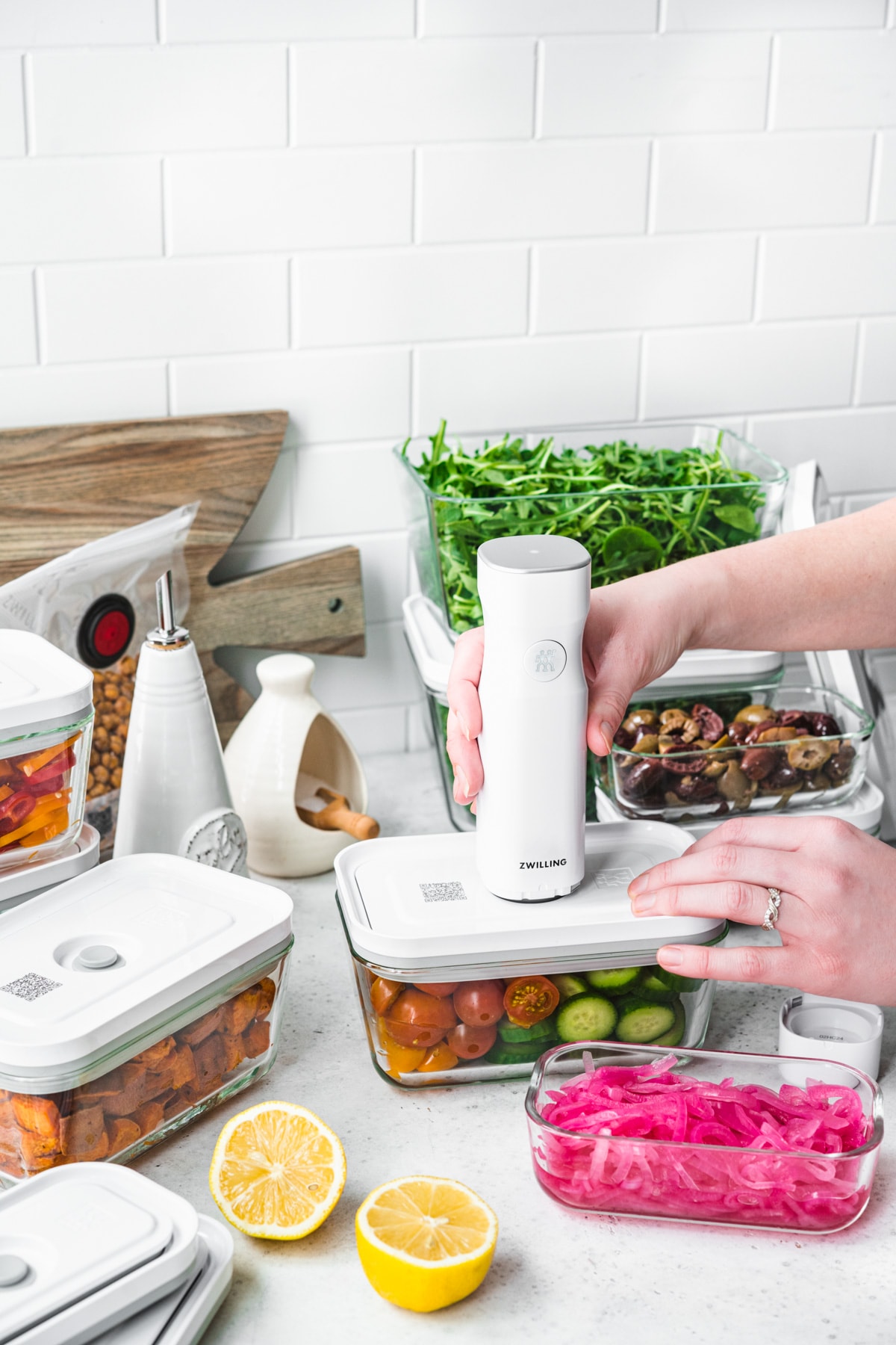 side view of person using Zwilling fresh and save vacuum sealer to seal salad meal prep materials. 