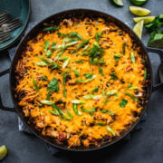 overhead view of vegan cheesy cauliflower bake with black beans and rice in large skillet.