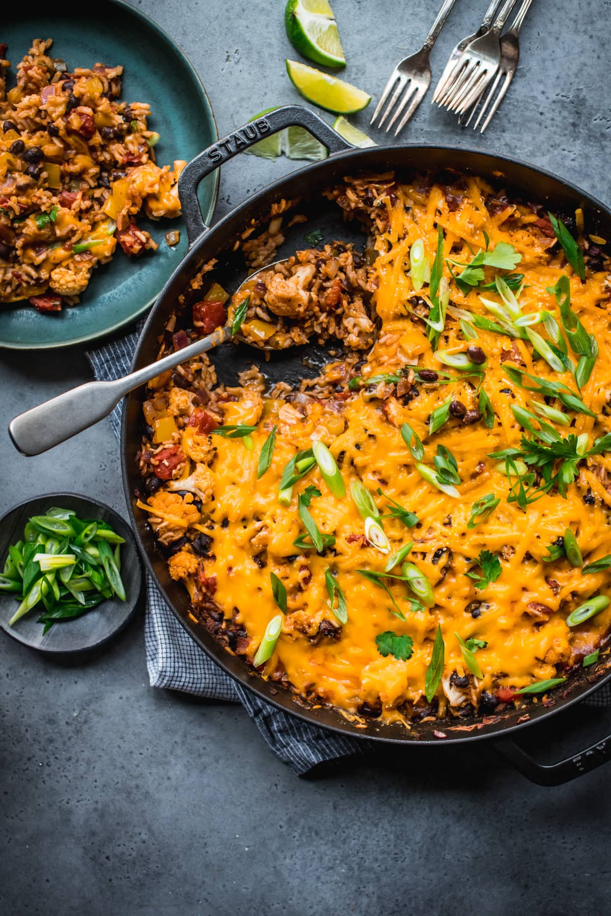 overhead view of vegan cheesy cauliflower bake with black beans and rice in large skillet. 