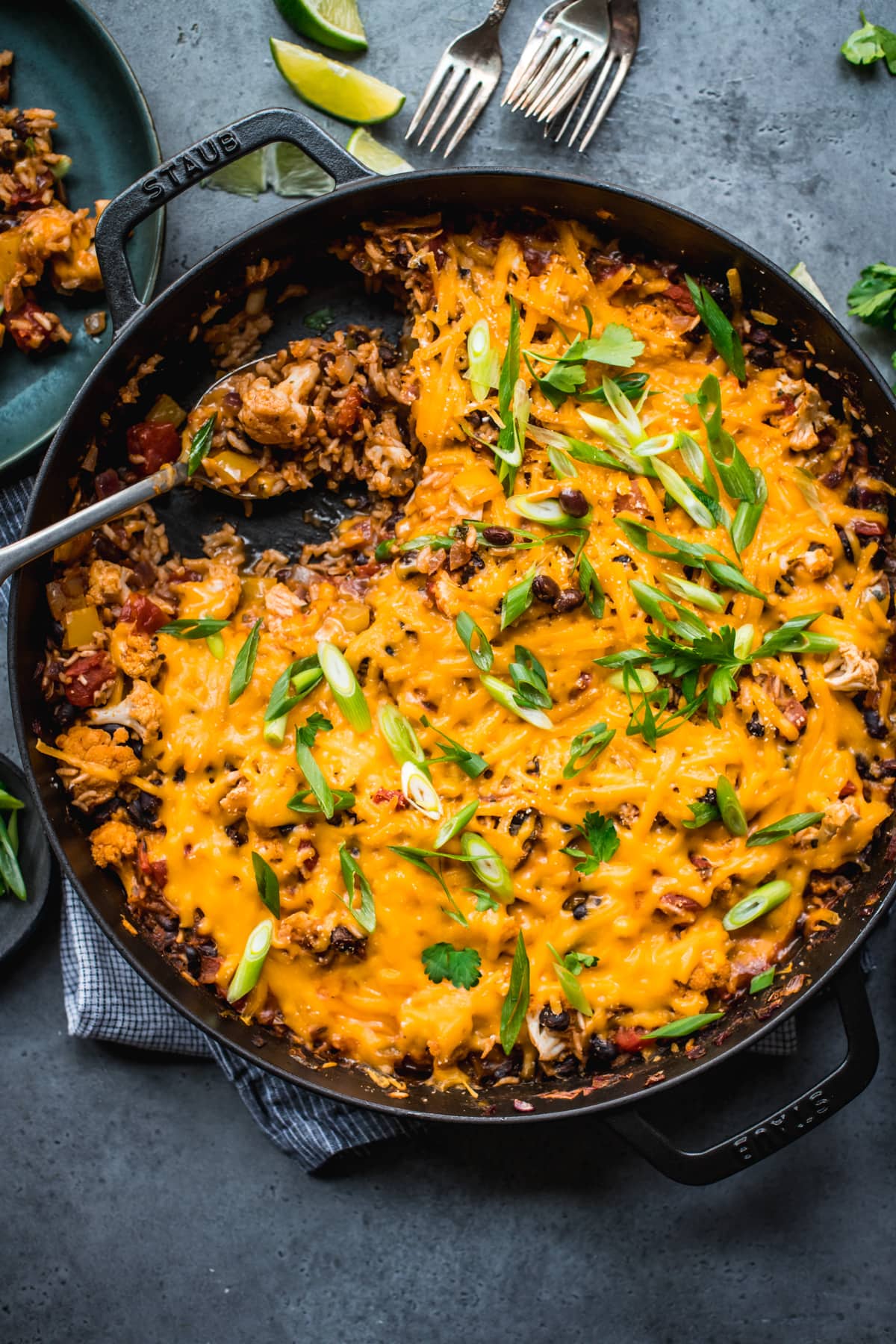 overhead view of vegan cheesy cauliflower bake with black beans and rice in large skillet. 