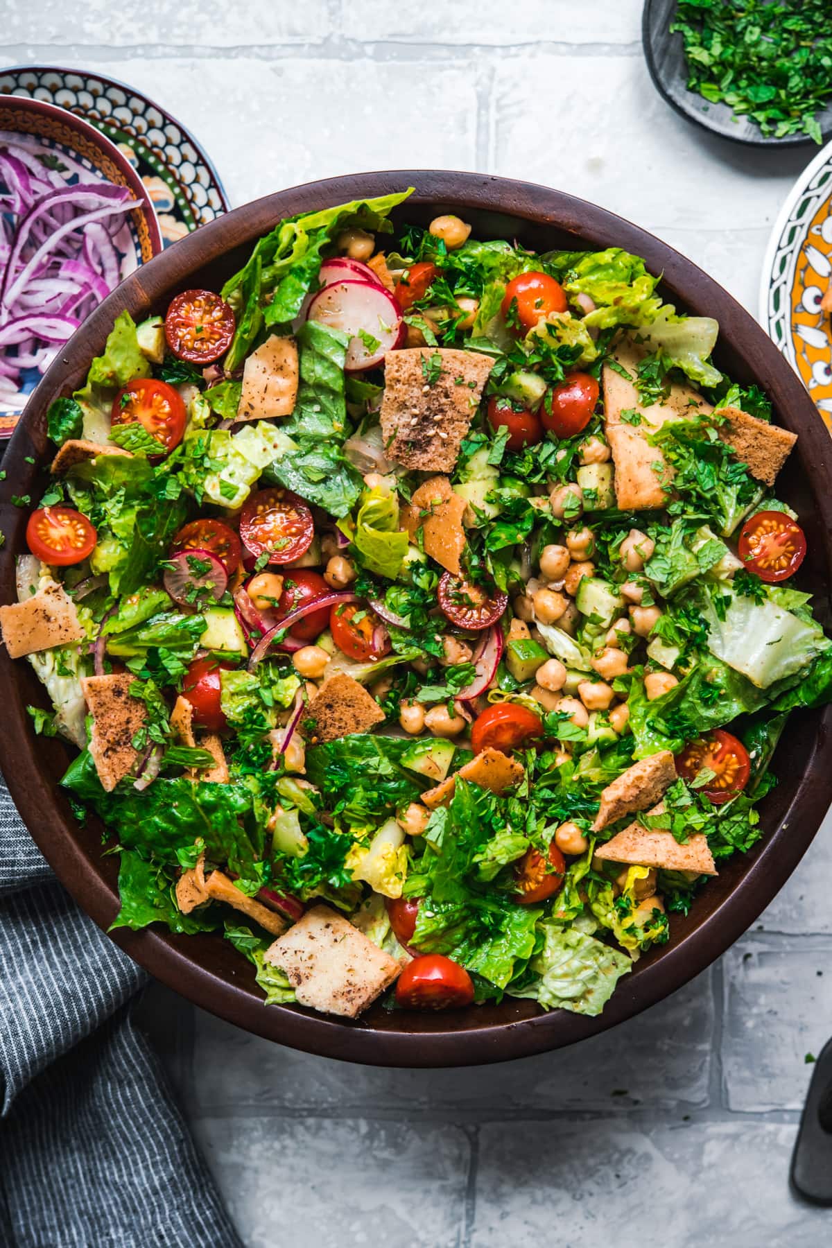 overhead view of chickpea fattoush salad with pita chips in wood salad bowl. 