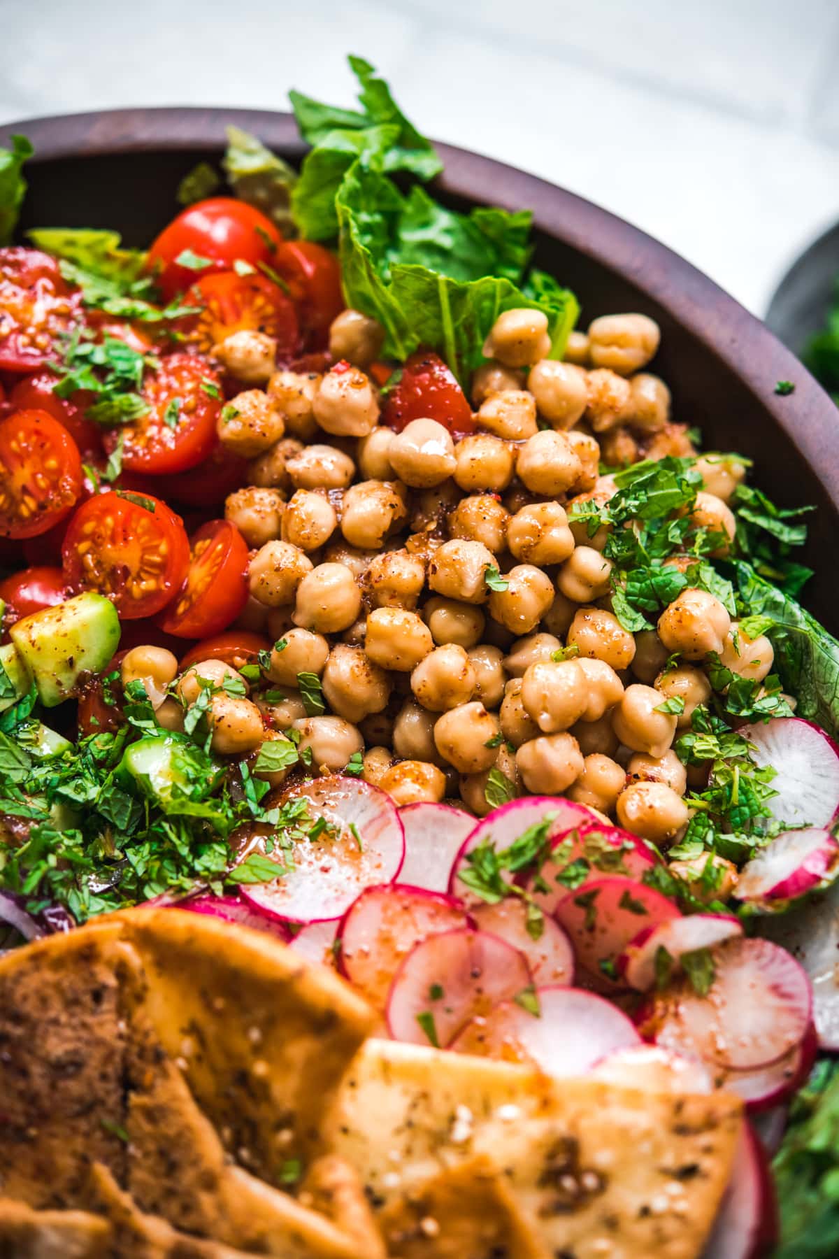 close up view of chickpeas in sumac dressing on fattoush salad. 