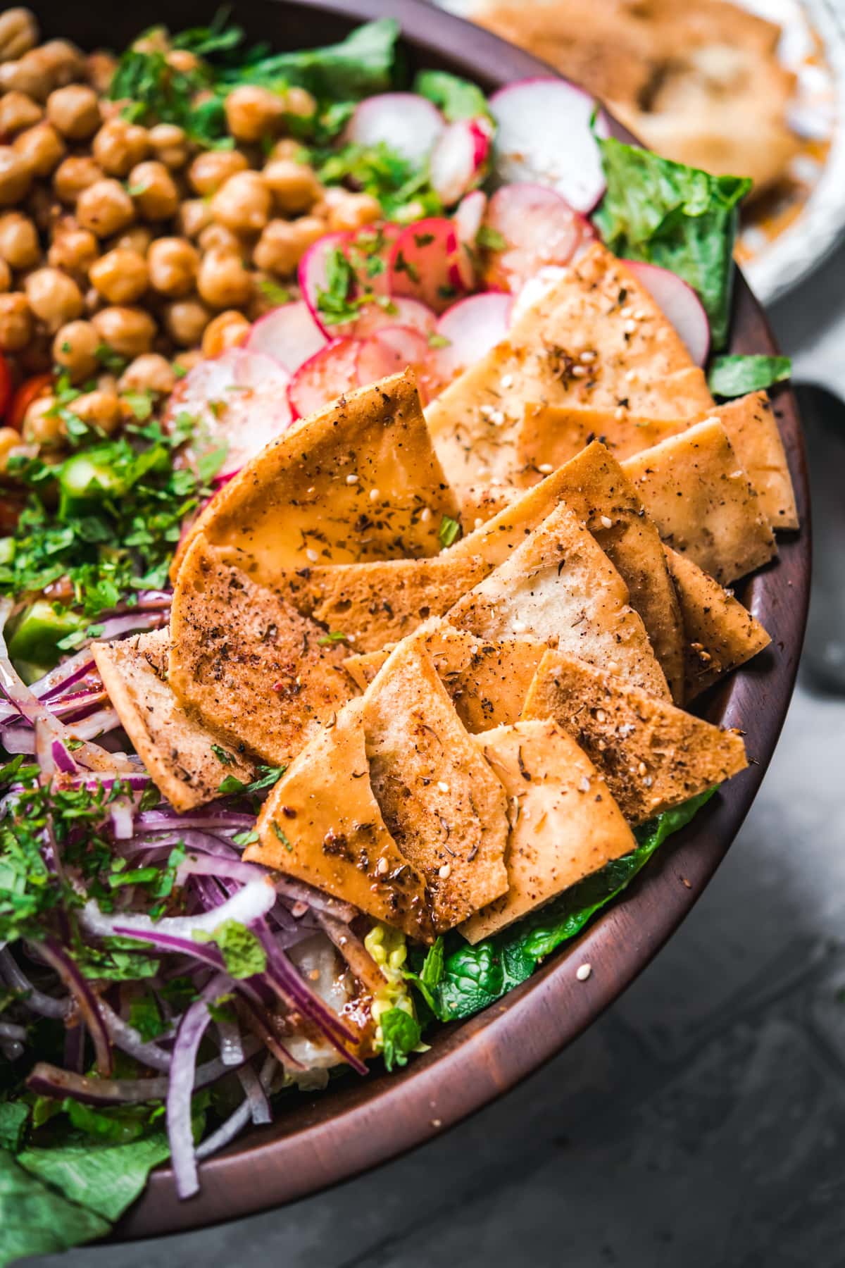 close up view of za'atar spiced pita chips on fattoush salad. 