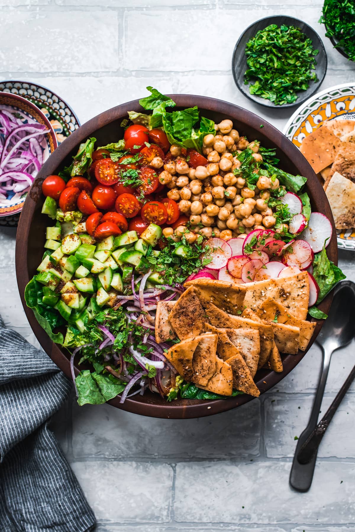 overhead view of chickpea fattoush salad with pita chips in wood salad bowl. 