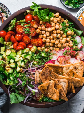 overhead view of chickpea fattoush salad with pita chips in wood salad bowl.
