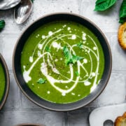 overhead view of vegan kale potato soup with yogurt drizzle and fresh basil.