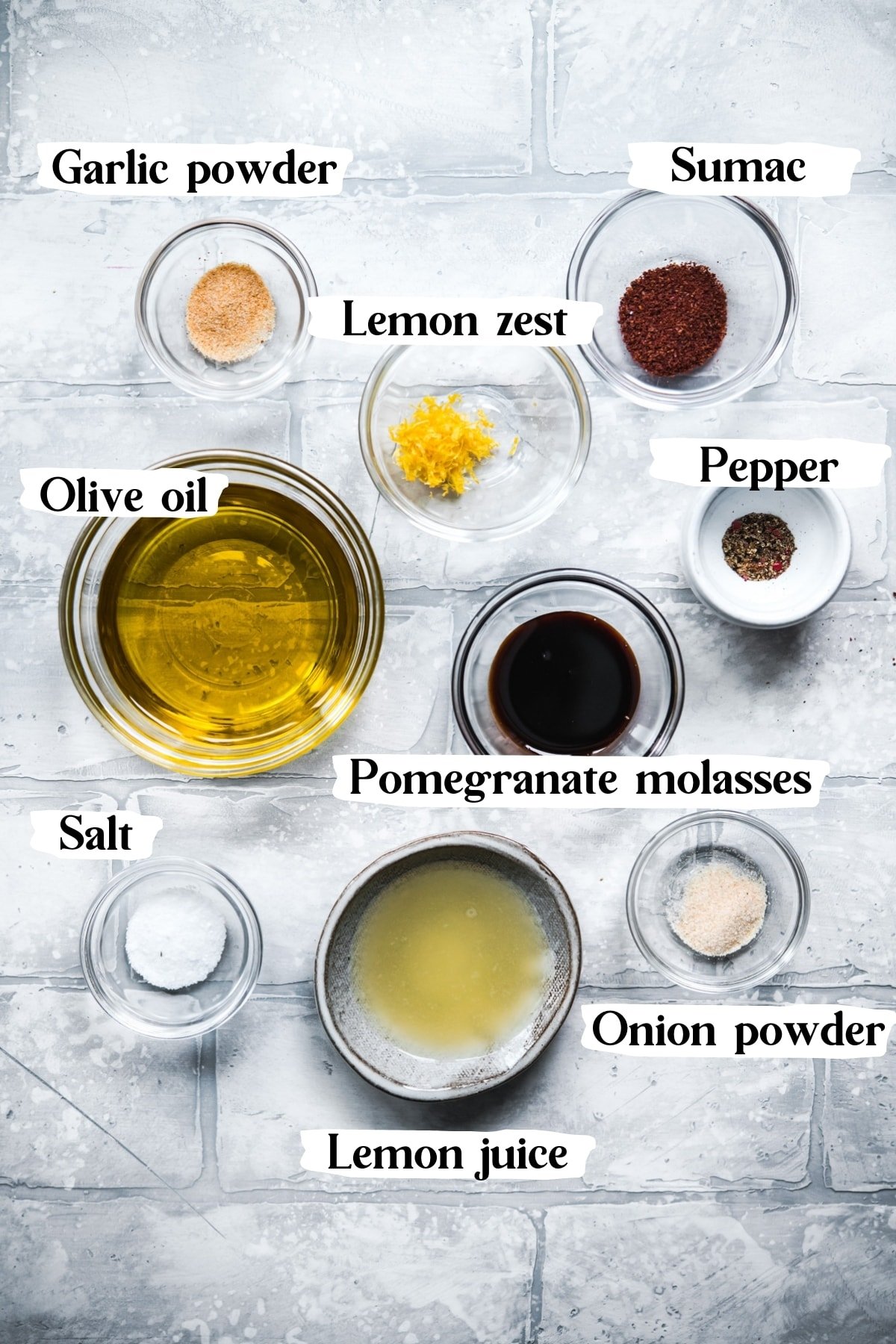 overhead view of ingredients for chickpea fattoush salad dressing in small bowls on tile backdrop. 