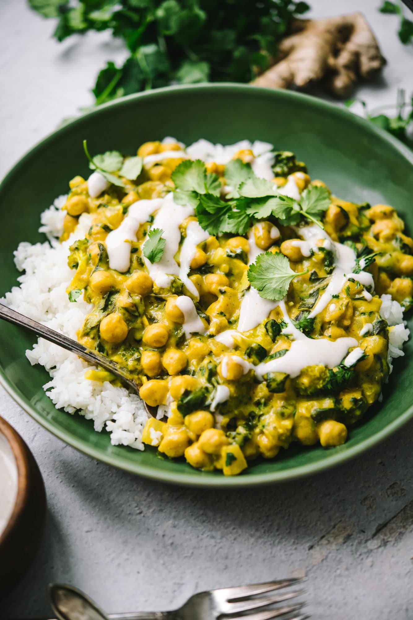 close up view of vegan mango chickpea curry over white rice in a green bowl.