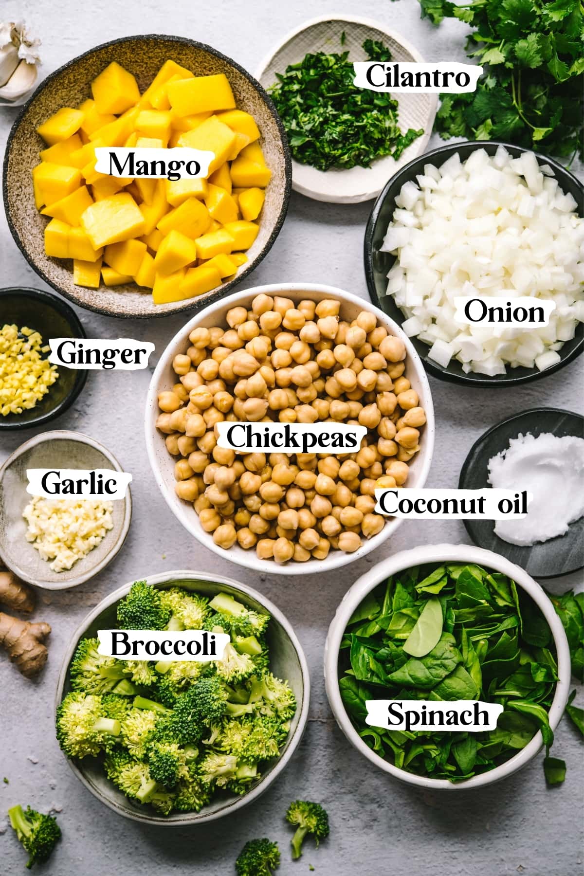 overhead view of ingredients for mango chickpea curry, including chickpeas, onion, coconut oil, cilantro, mango and more.