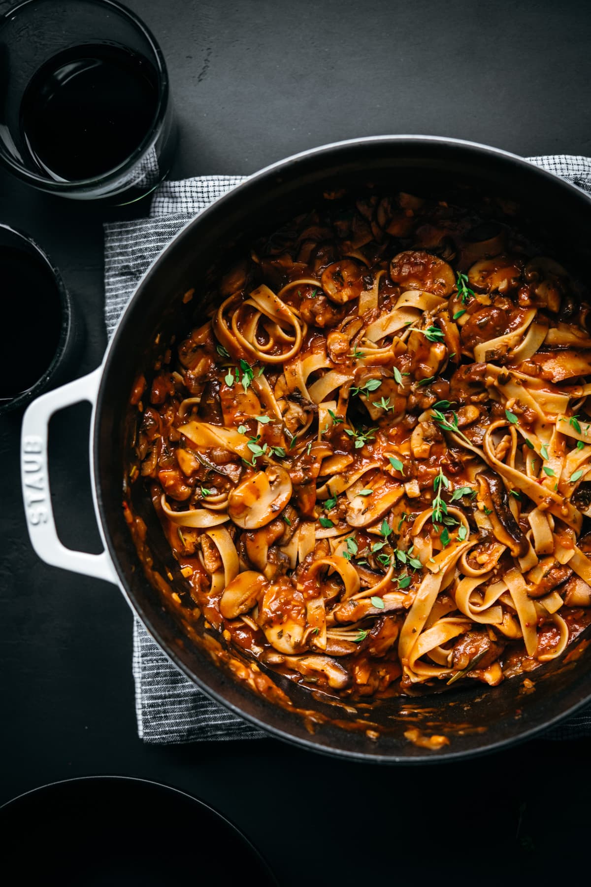 overhead view of vegan mushroom ragu over pasta in a large white dutch oven. 