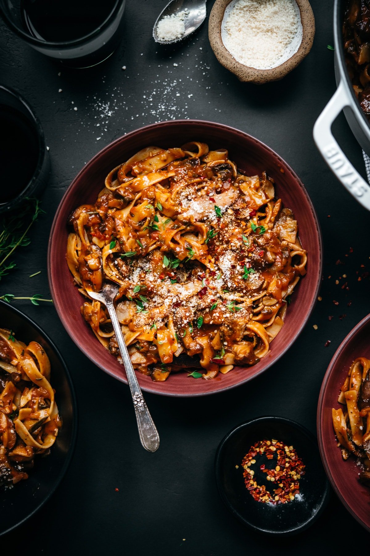 overhead view of vegan mushroom ragu over pasta in a red bowl. 