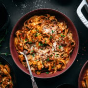 overhead view of vegan mushroom ragu over pasta in a red bowl.