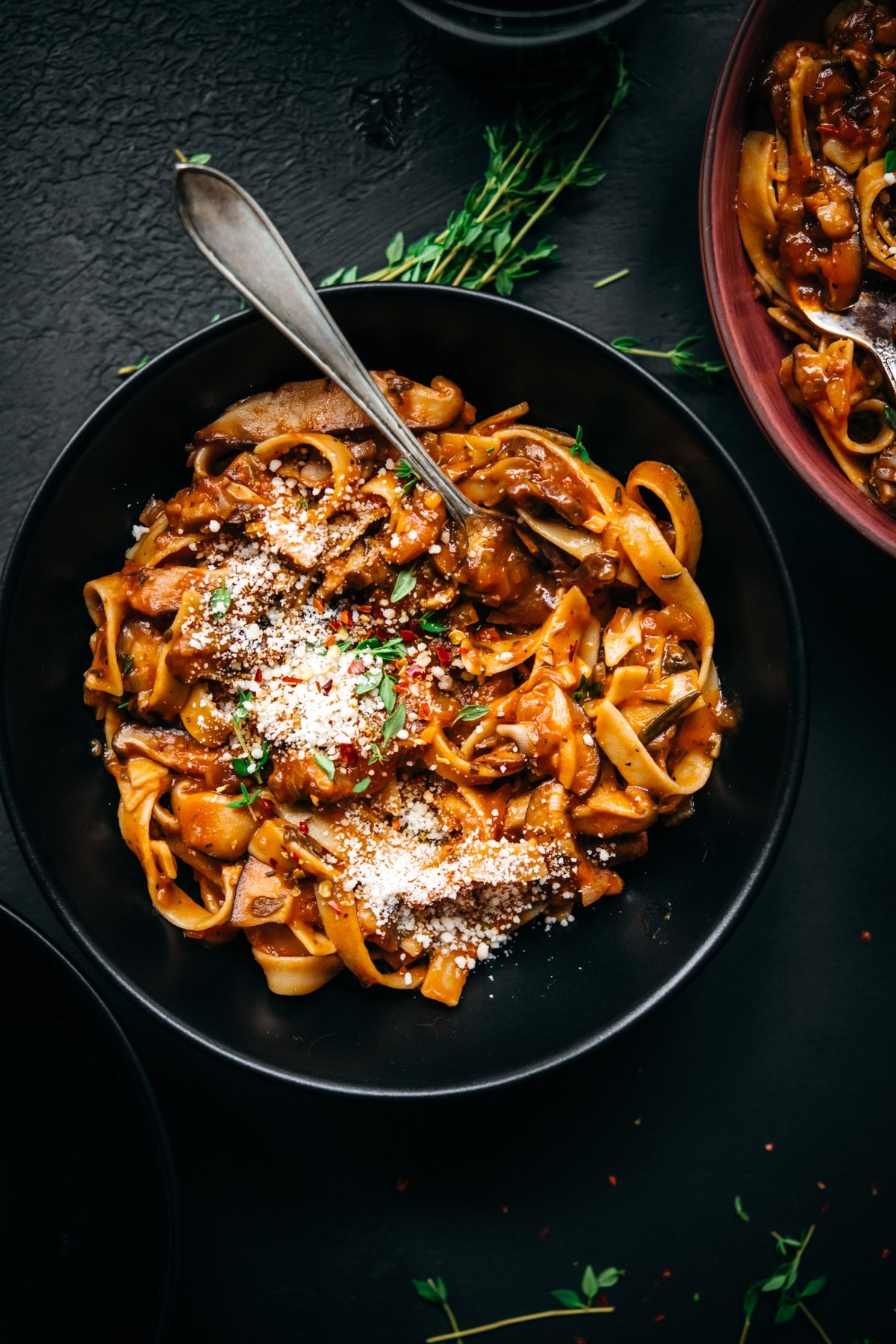 overhead view of vegan mushroom ragu over pasta in a black bowl.