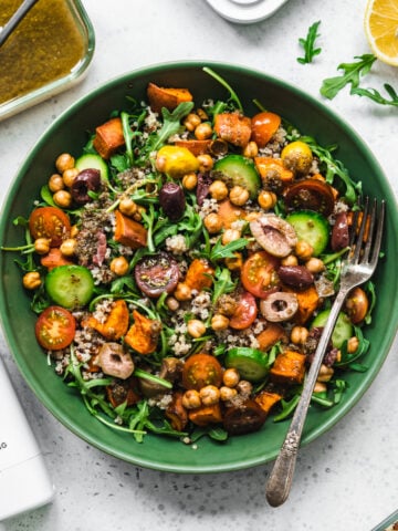 overhead view of quinoa arugula and sweet potato salad in a green bowl.