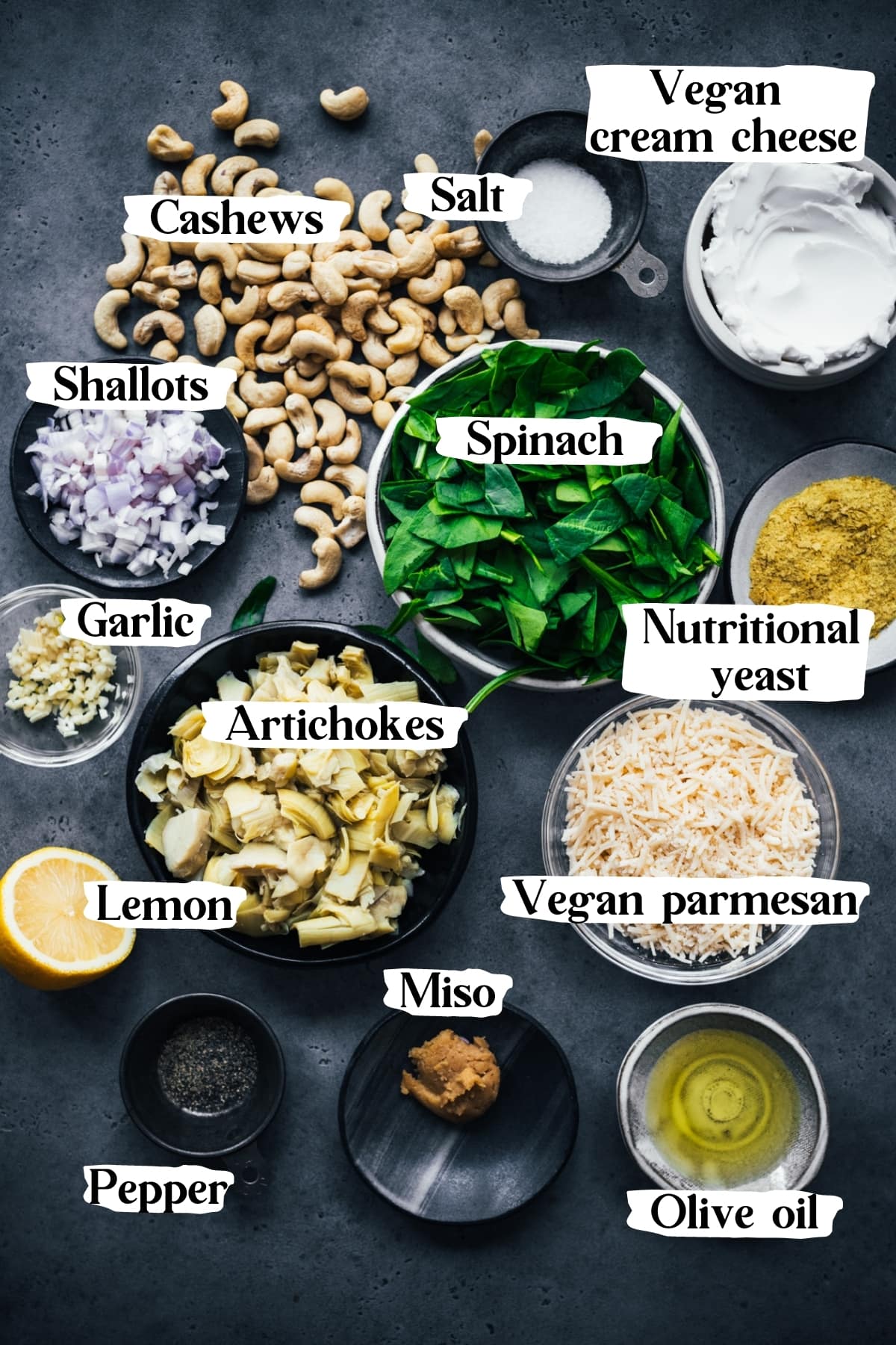 overhead view of ingredients for vegan spinach artichoke dip, including cashews, vegan cheese, spinach, artichokes, shallots. 