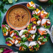 overhead view of tofu vegetable summer rolls on a circular platter with bowl of miso dipping sauce.