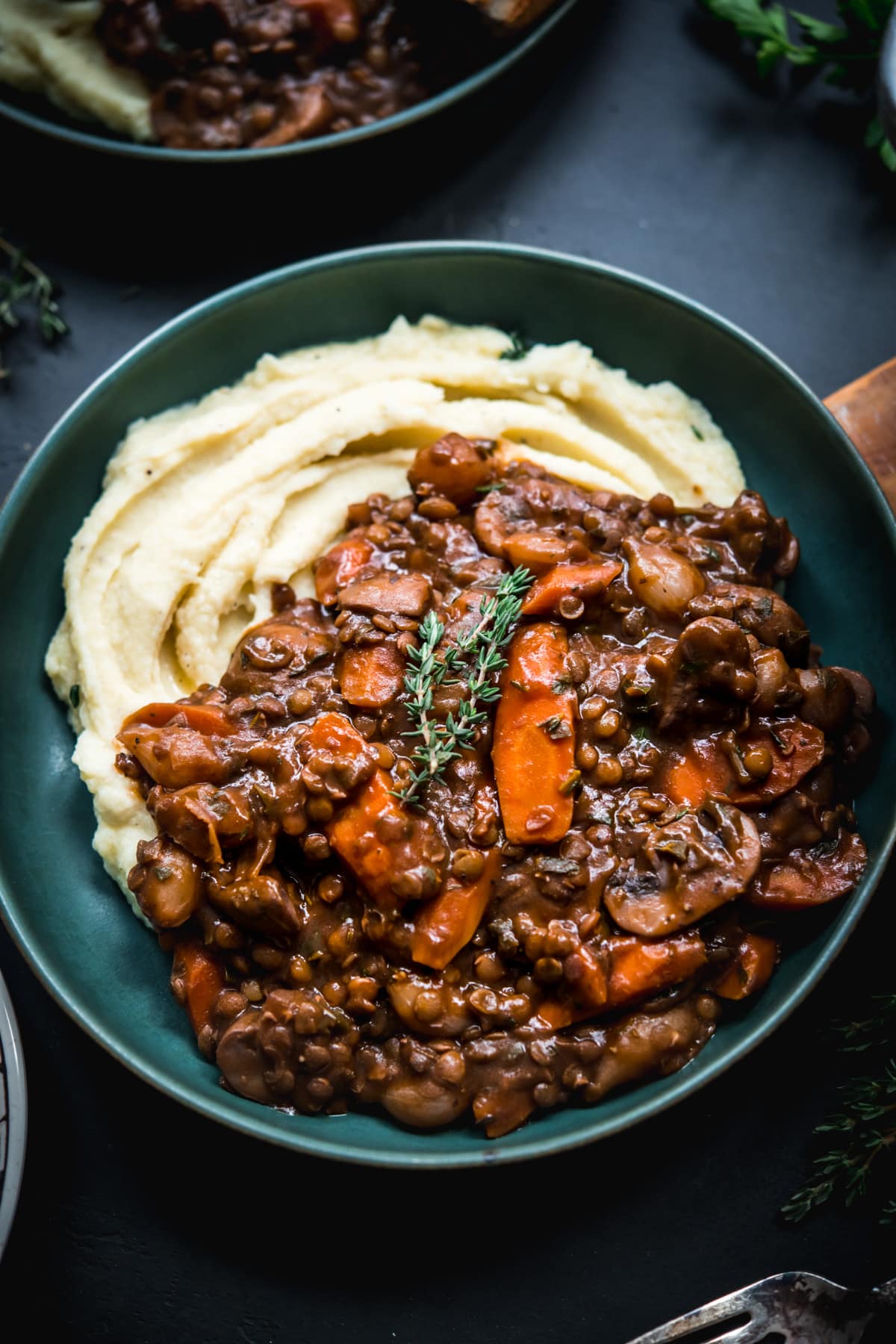 close up view of vegan lentil and mushrooom coq au vin over mashed potatoes in a bowl. 