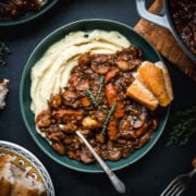 overhead view of vegan lentil and mushrooom coq au vin over mashed potatoes in a bowl.