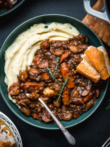 overhead view of vegan lentil and mushrooom coq au vin over mashed potatoes in a bowl.