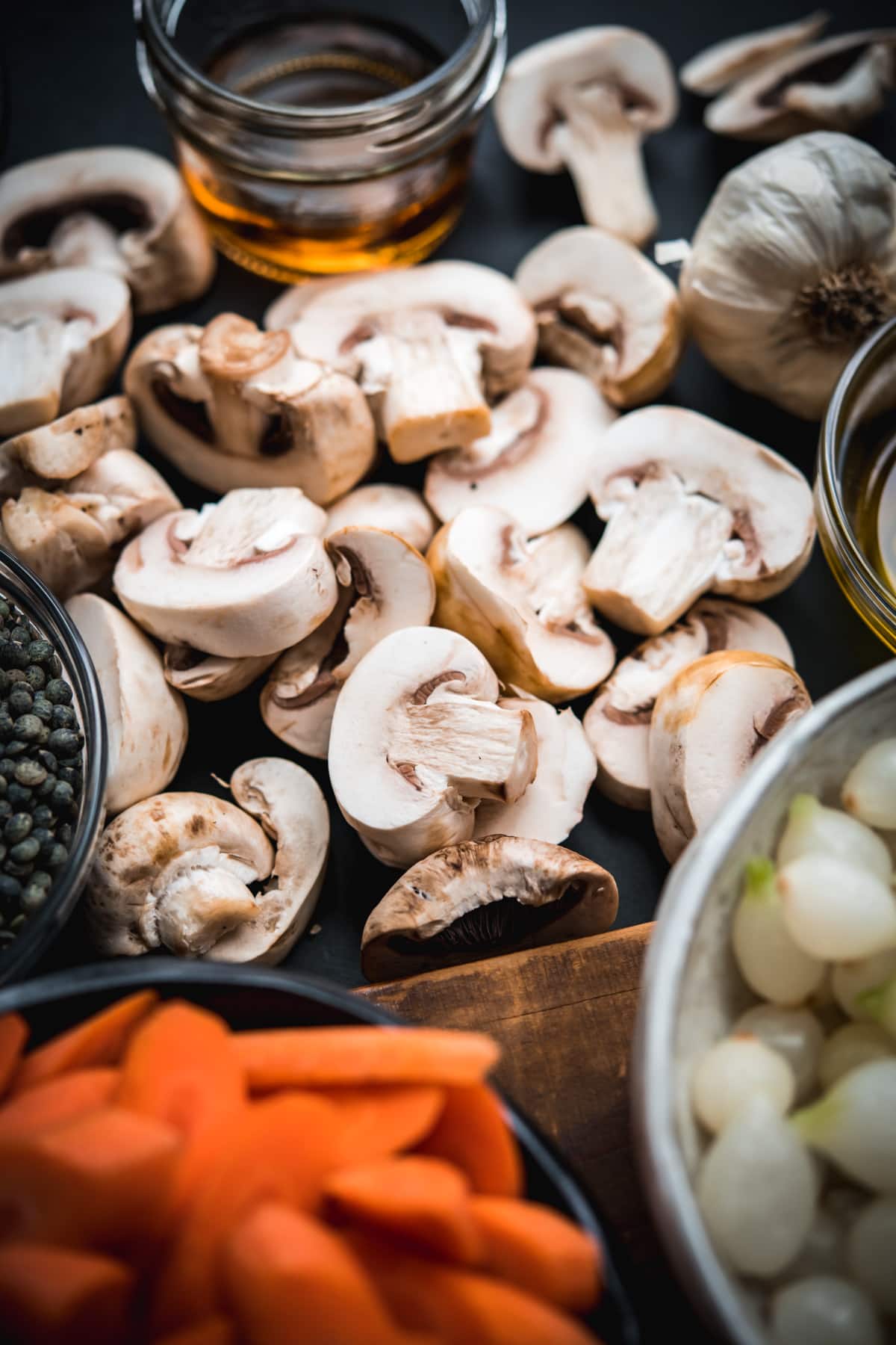 close up view of sliced button mushrooms with other ingredients for vegan coq au vin. 