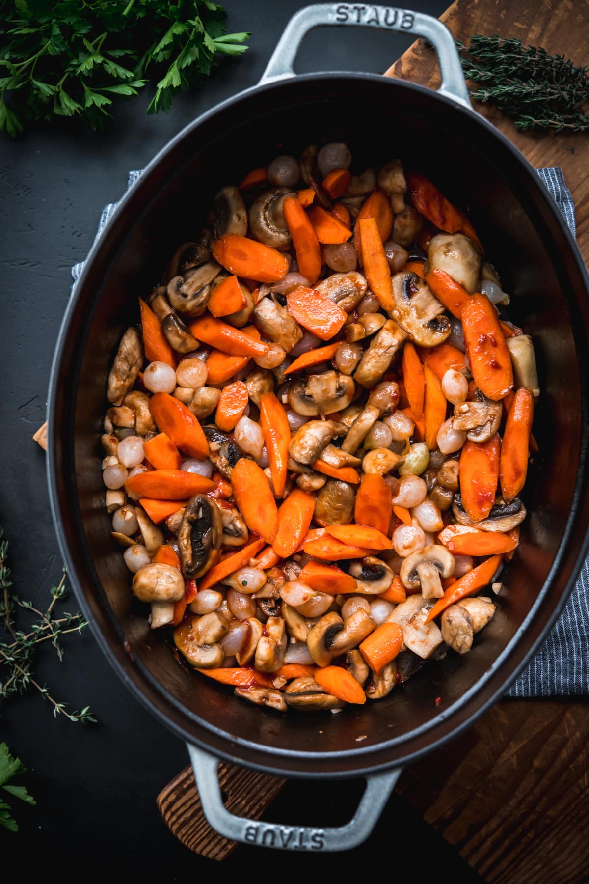 carrots, mushrooms and pearl onions being sautéed in a large dutch oven.