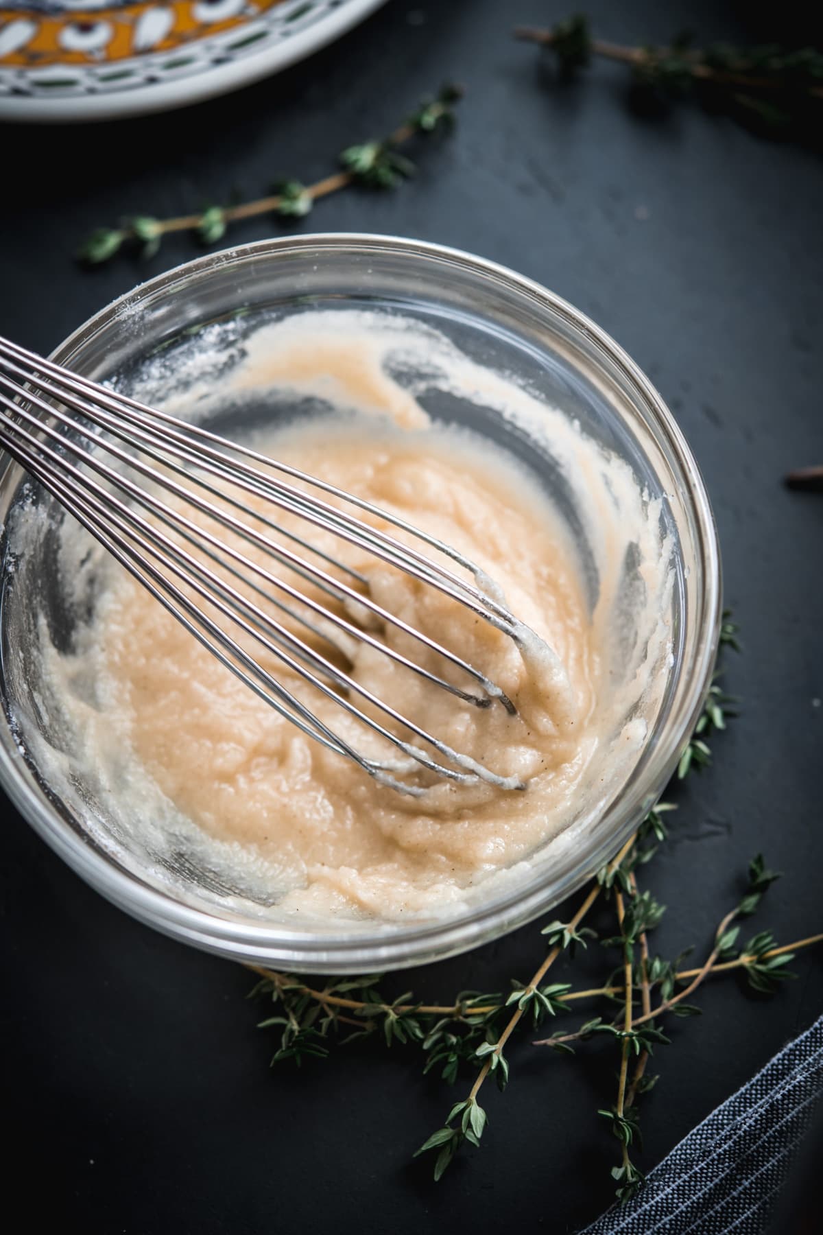 close up view of butter and flour roux in a small glass bowl with whisk.