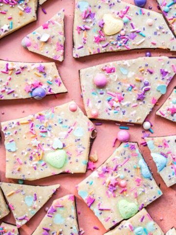 overhead view of vegan white chocolate bark broken into pieces topped with sprinkles.