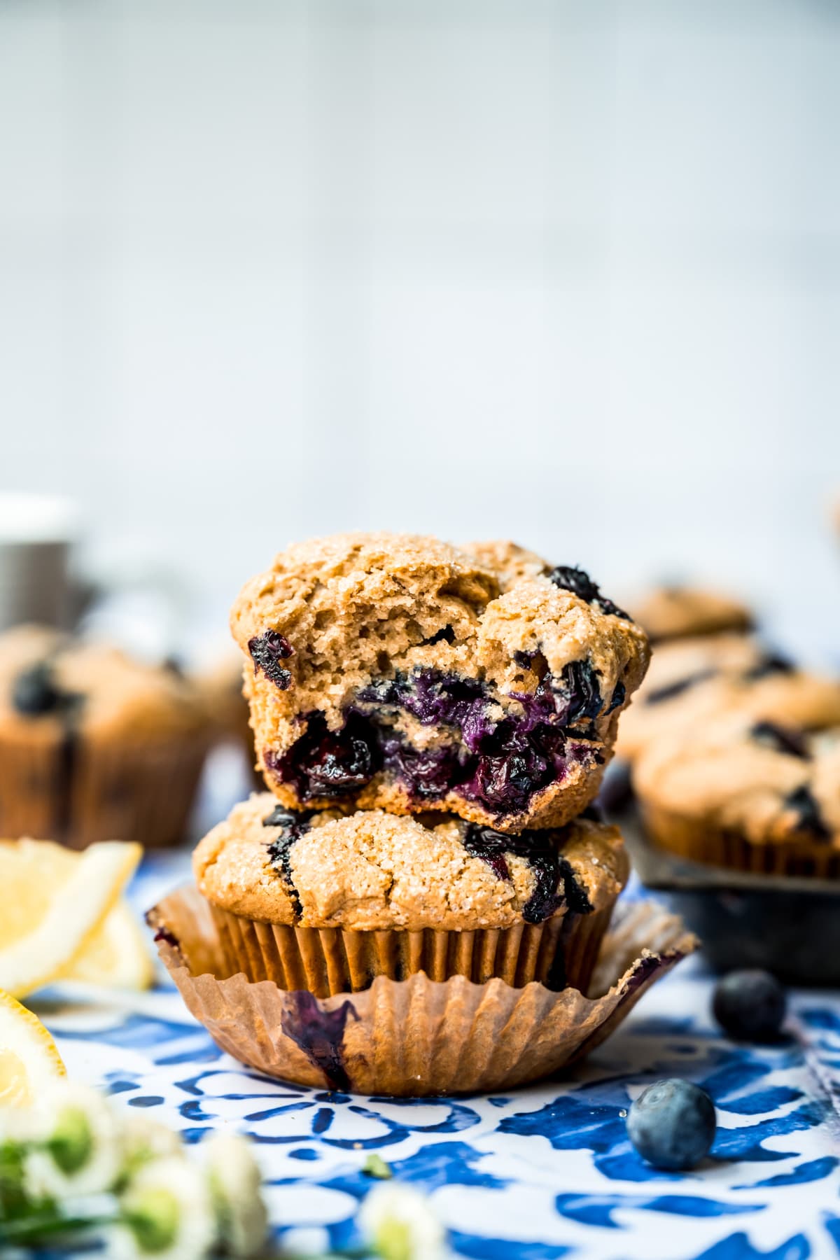 close up side view of two stacked vegan blueberry muffins with the top one cut in half. 