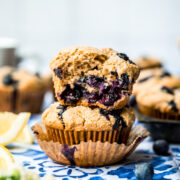 close up side view of two stacked vegan blueberry muffins with the top one cut in half.