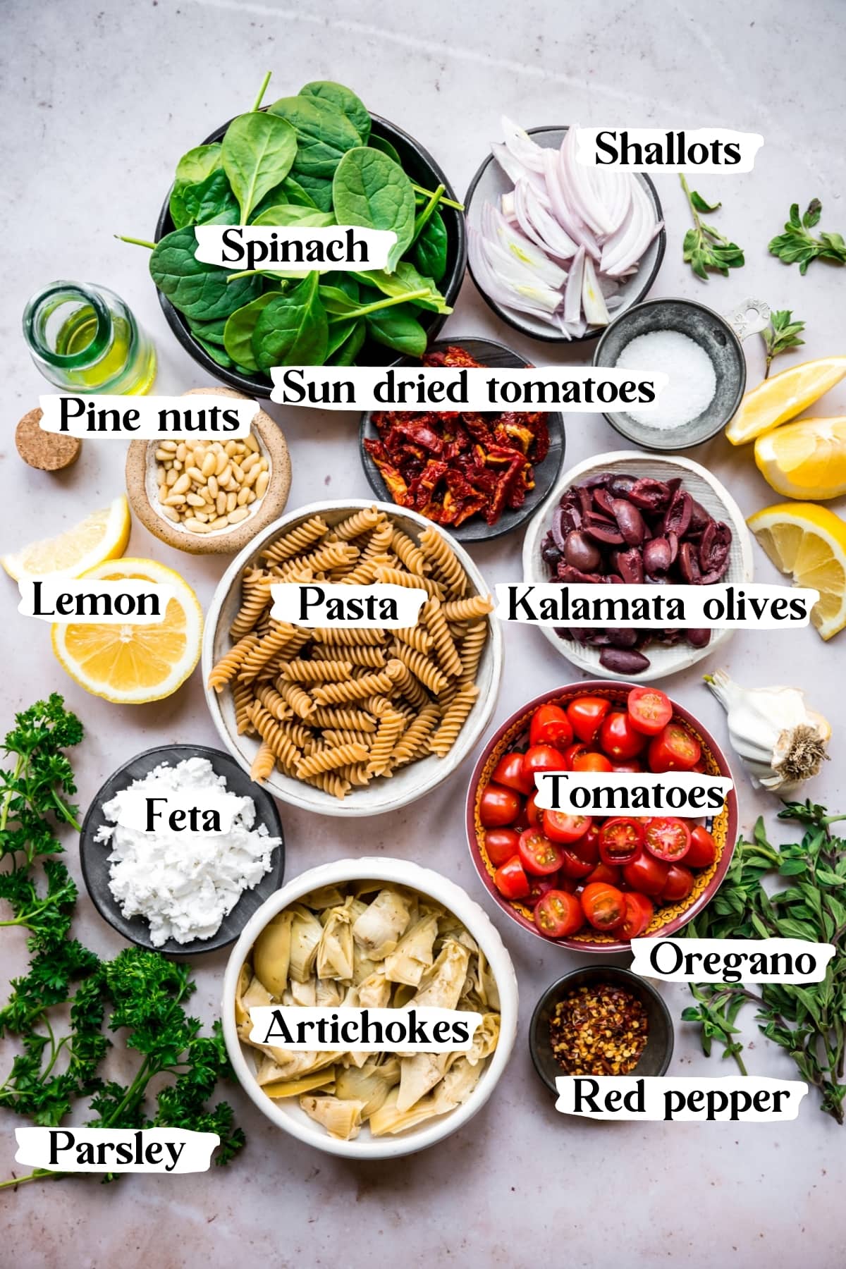 overhead view of ingredients for greek pasta in small bowls. 