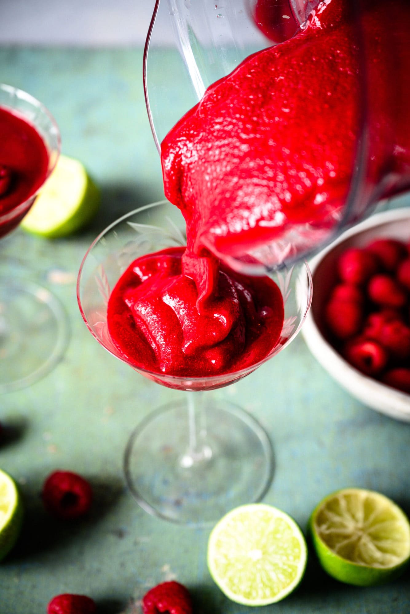 pouring frozen raspberry daiquiri into cocktail glass from blender. 