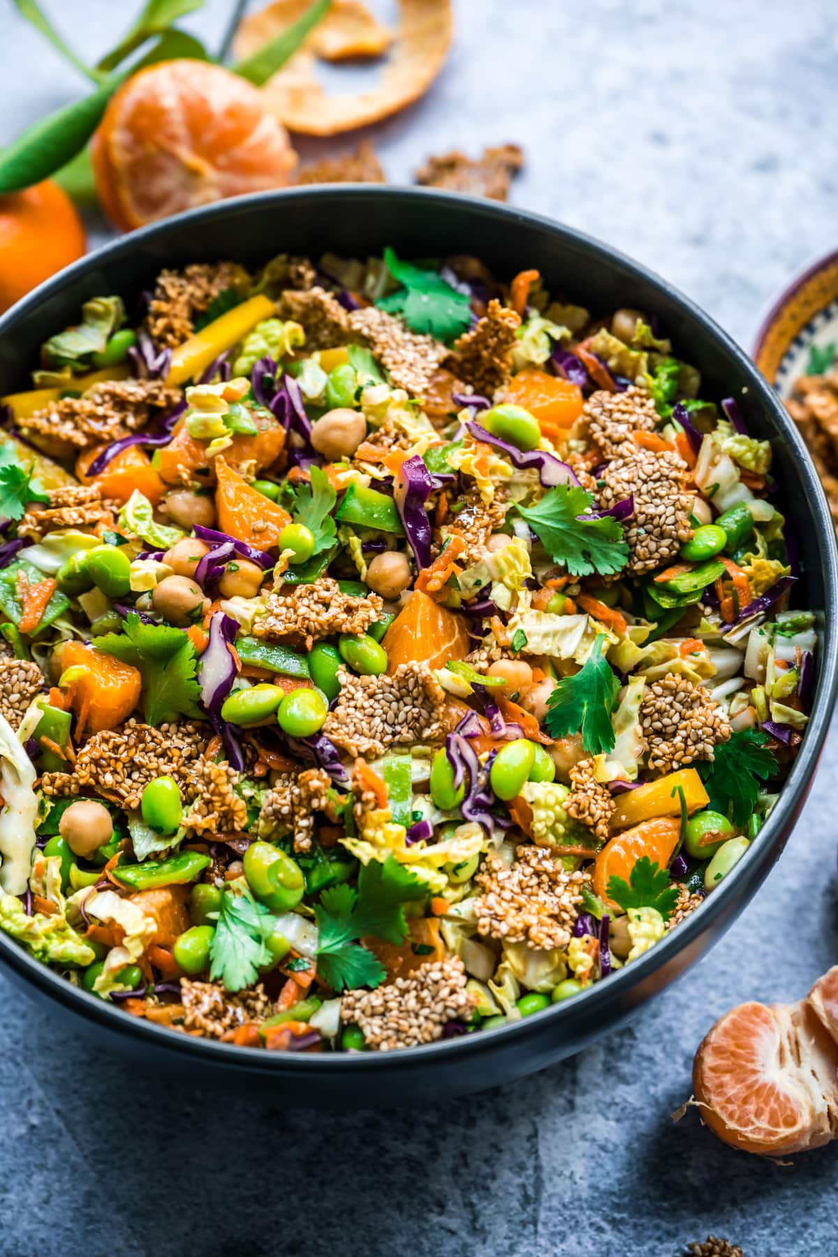 close up view of vegan sesame chickpea salad in a large bowl with edamame, cabbage and sesame brittle. 