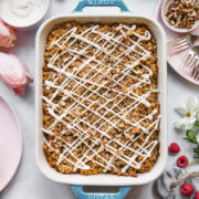 overhead view of vegan carrot cake baked in a blue baking dish with cream cheese glaze.