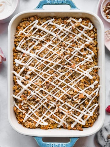 overhead view of vegan carrot cake baked in a blue baking dish with cream cheese glaze.