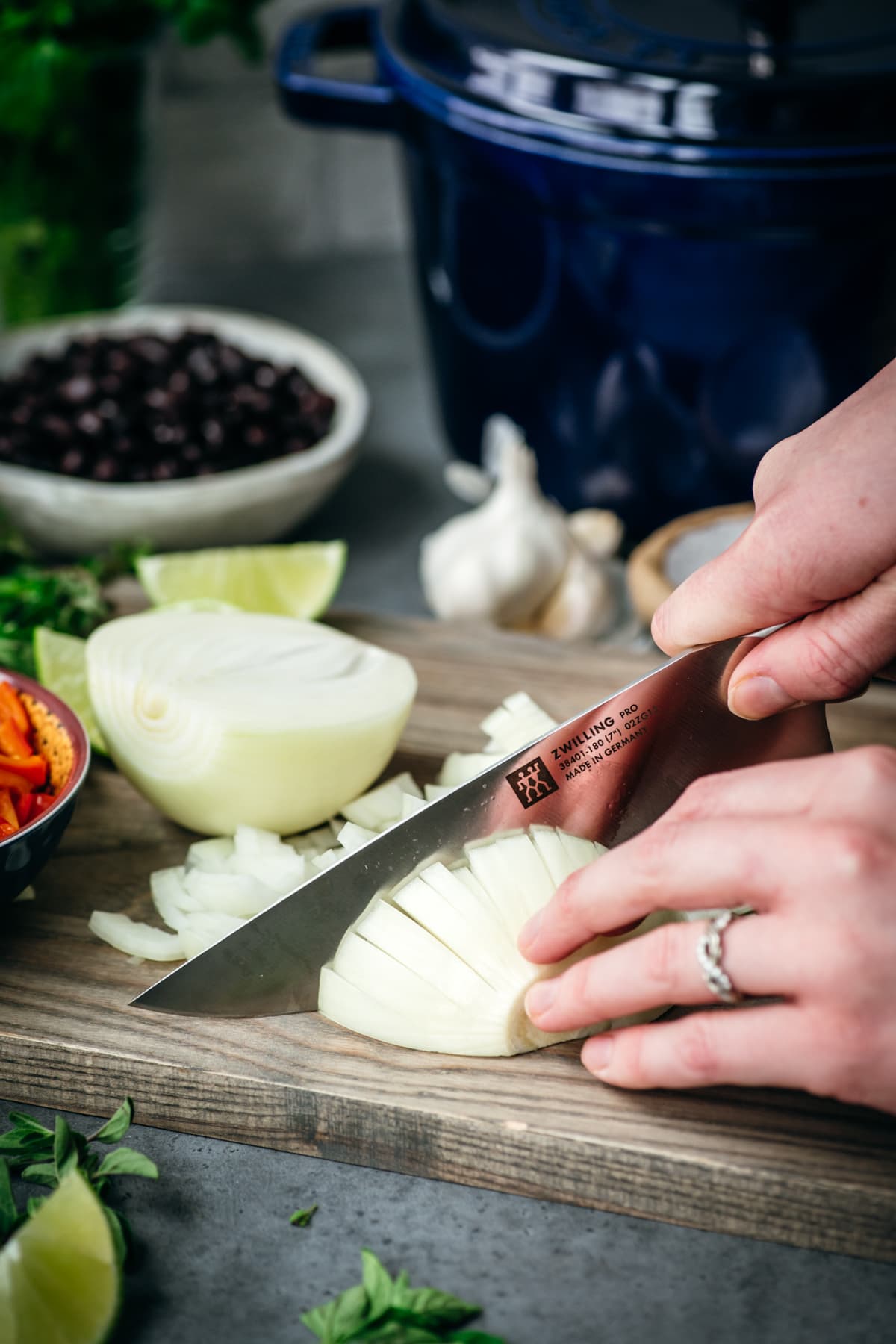 close up of slicing a yellow onion on a cutting board. 