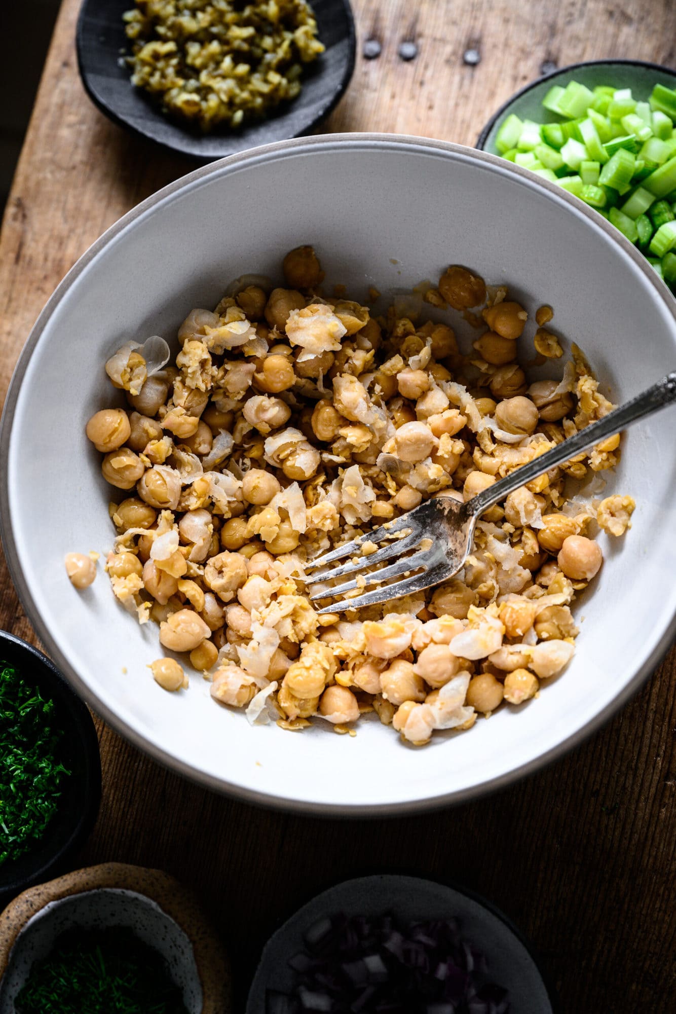 close up view of mashed chickpeas in a bowl with a fork.