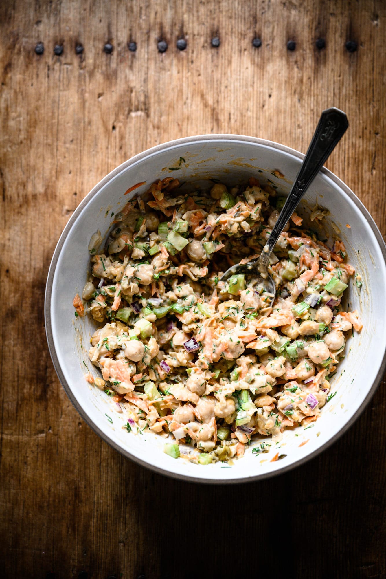 overhead view of vegan chickpea tuna salad in a white mixing bowl with spoon.